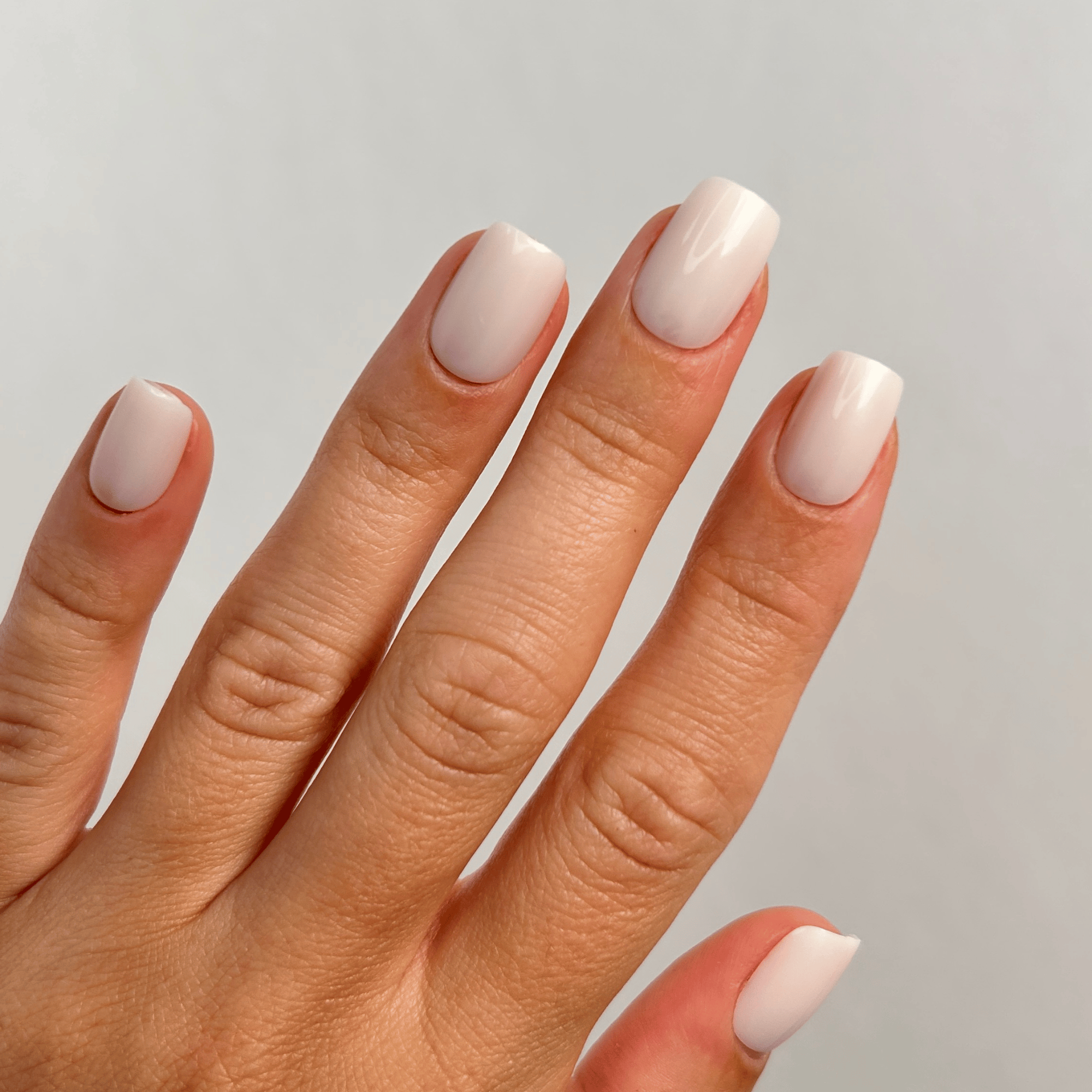 Creamy White Medium Square Press-On Nails an der Hand getragen